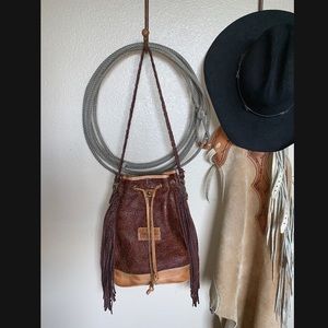 Tooled leather purse with fringe detailing.